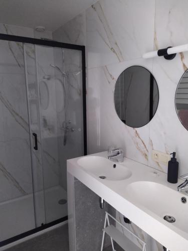 La salle de bains blanche est pourvue d'une douche et d'un lavabo. dans l'établissement Gîte Le Framboisier V de la distillerie Bio Spirit Belgium, à Neufchâteau