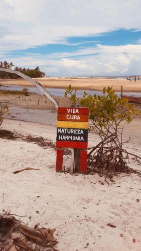 a sign in the sand on a beach at Natal Chalés Nova Caraiva in Caraíva