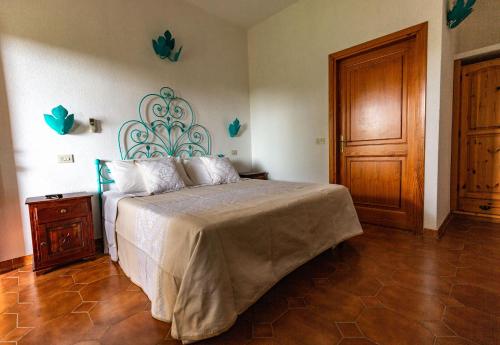 - une chambre avec un lit et une porte en bois dans l'établissement Turismo Rurale CUDACCIOLU, à Arzachena