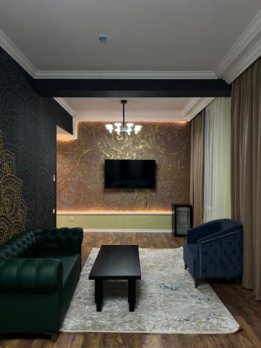 a living room with a couch and a tv at WIND HOTEL in Shymkent