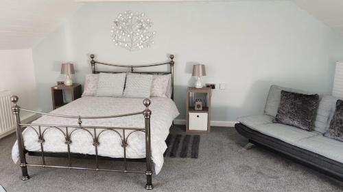 a bedroom with a bed and a couch and a chandelier at The Stables in Tregaron
