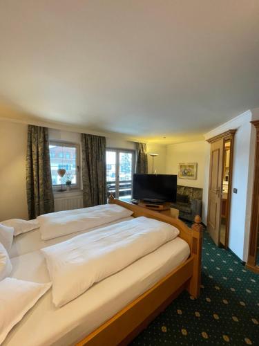 a bedroom with three beds and a flat screen tv at Wohlfühlhotel Berwanger Hof in Obermaiselstein