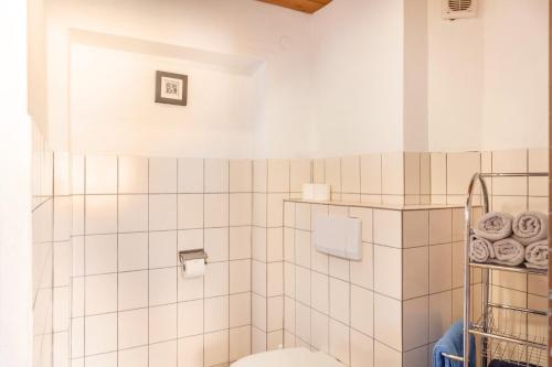 a white tiled bathroom with a toilet and towels at Fewo 1 Haus am Lärchenhang in Leutasch