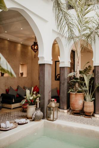 a pool in a hotel lobby with palm trees at Riad Alnadine in Marrakech