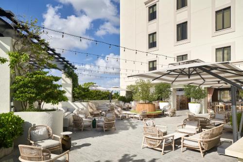 a patio with chairs and umbrellas in front of a building at THesis Hotel Miami Coral Gables, Curio Collection by Hilton in Miami