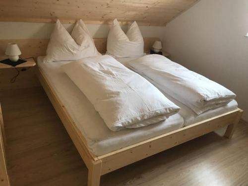 un letto con lenzuola e cuscini bianchi di Chalet Schröder a Klippitztorl