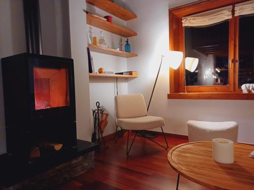 a living room with a fireplace and a table and chairs at Infinity Mountain View in Angoustrine