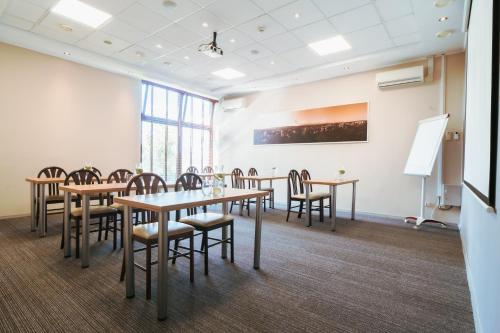 a conference room with tables and chairs and a whiteboard at Mercure Cieszyn in Cieszyn