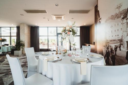a long white table with white chairs and flowers at Mercure Cieszyn in Cieszyn