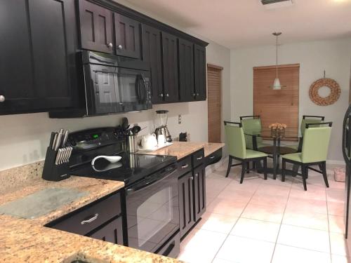 a kitchen with black cabinets and a table with chairs at Sunny South Facing Pool with Hot Tub and Lake View Near Disney in Kissimmee