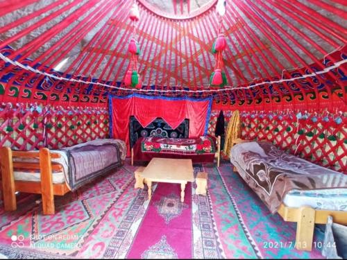 a room with two beds and a table in a yurt at Karakol Yurt Lodge in Karakol