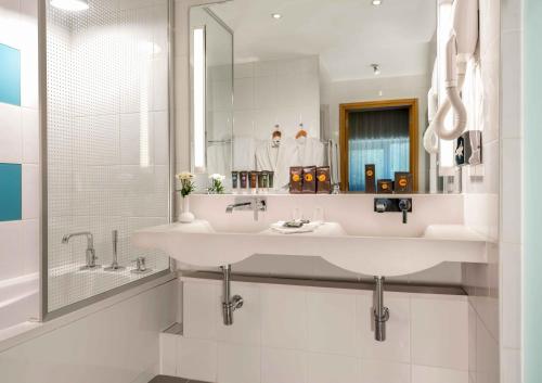 a white bathroom with a sink and a mirror at Novotel Gaziantep in Gaziantep