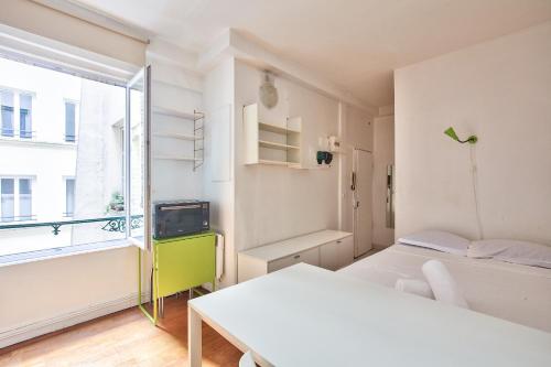 une chambre avec deux lits, une table et une fenêtre dans l'établissement Charmant studio Paris 3 Marais, à Paris