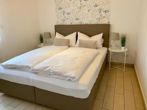 a large bed with white sheets and pillows at Ferienhäuser mit Seeblick direkt am Plauer See in Plau am See