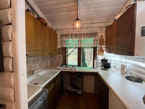 a small kitchen with a sink and a window at Przytulny domek w lesie blisko rzeki in Ryczywół