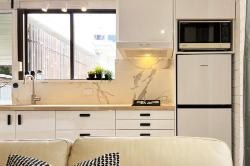 a white kitchen with a couch and a microwave at Studio C by Breckler Park in Perth