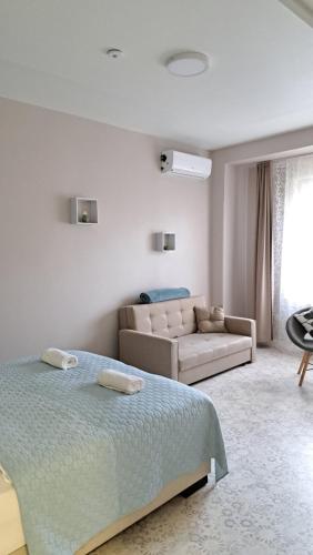 a white bedroom with a bed and a couch at Eper Apartman in Szeged