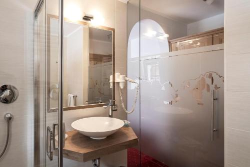 La salle de bains est pourvue d'un lavabo et d'une douche en verre. dans l'établissement Garni Schenk, à Selva di Val Gardena