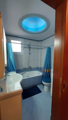 e bagno con vasca, servizi igienici e soffitto blu. di Makarios Apartment Near Athens Aiport a Spata