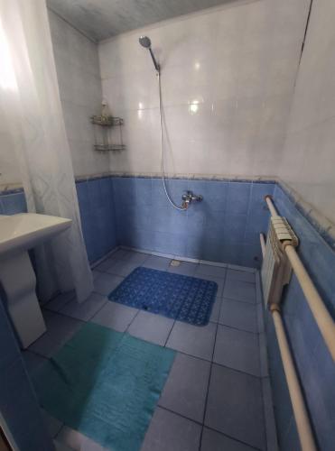 y baño con bañera y ducha con azulejos azules. en Karakol Yurts Camp, en Karakol