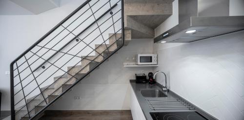 a kitchen with a staircase with a sink and a microwave at Apartamentos Rosa Velázquez in Merida