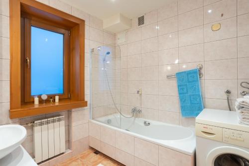 bagno con vasca, lavandino e lavatrice di Apartamenty w Gorcach a Nowy Targ