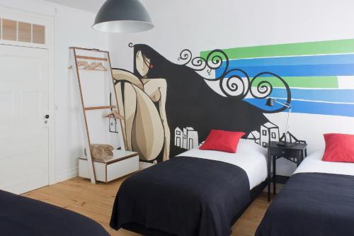 a bedroom with two beds and a painting on the wall at Azorean Urban Lodge in Ponta Delgada