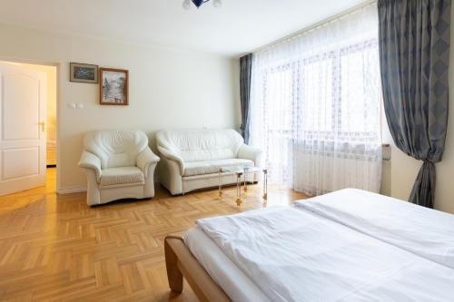 a bedroom with two chairs and a bed and a window at Apartamenty w Gorcach in Nowy Targ