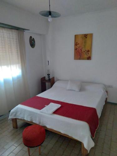 een slaapkamer met een groot bed met een rode stoel bij La estacion in Tandil