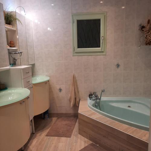 ein Badezimmer mit einer Badewanne, einem Waschbecken und einem Spiegel in der Unterkunft REVES BLEUS in Crans