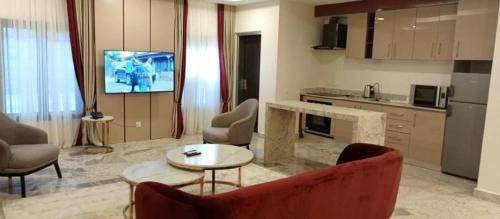 sala de estar con sofá rojo y cocina en Fahrenheit Apartments, en Abuja