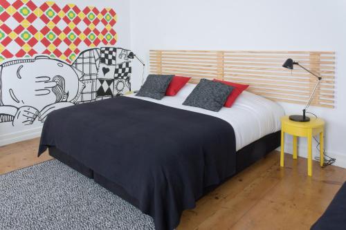 a bedroom with a bed with a black blanket and red pillows at Azorean Urban Lodge in Ponta Delgada