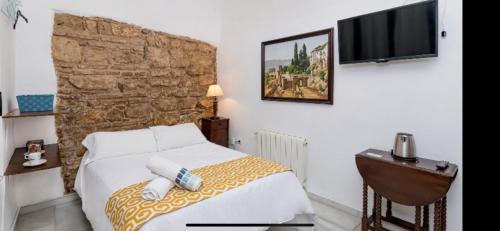 a bedroom with a bed and a tv on a wall at Judería Suites in Córdoba