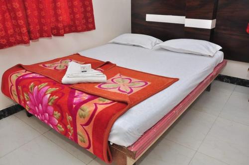 a bed with a colorful blanket and shoes on it at Hotel Sai Sulochana in Shirdi