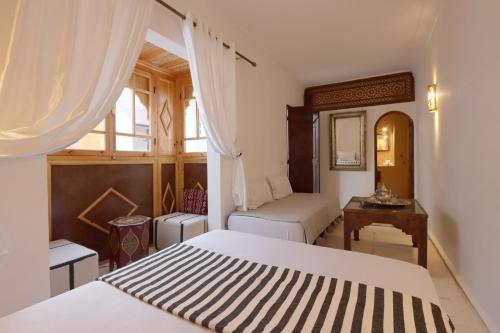 1 Schlafzimmer mit 2 Betten, einem Schreibtisch und einem Fenster in der Unterkunft Riad Jenan L'mouassine in Marrakesch