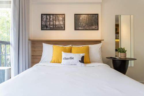 1 dormitorio con cama blanca y almohadas amarillas en Smart Charlie Parque Augusta Mackenzie, en São Paulo