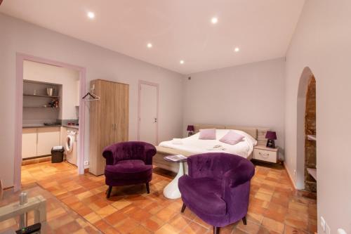 サルラ・ラ・カネダにあるL'Appartement du "Coup de Coeur de Sarlat"のベッドルーム(紫色の椅子、ベッド付)