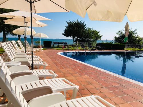 - une rangée de chaises et de parasols à côté de la piscine dans l'établissement Villa Sun Palace, à Sveti Vlas