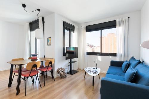 sala de estar con sofá azul y mesa en Urban Chill Apartments by Olala Homes, en Hospitalet de Llobregat