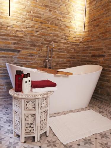 a bath tub in a bathroom with a brick wall at El Violin Experiencia Adults only in Melegis