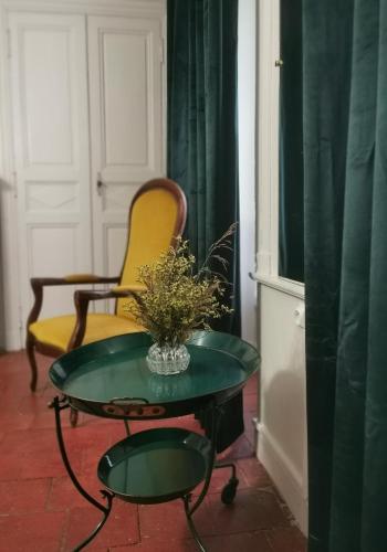 een stoel en een tafel met een vaas met bloemen bij Alice & Jeanne - Chambre d'hôte in Lectoure