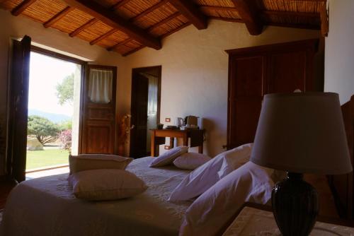 ein Schlafzimmer mit einem Bett mit einer Lampe und einem Fenster in der Unterkunft Stazzu Barecca B&B in Cugnana Verde