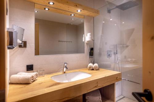 a bathroom with a sink and a shower with a mirror at Gamsalm in Kals am Großglockner