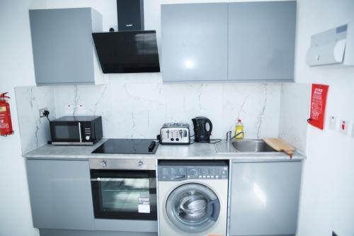 eine Küche mit einer Waschmaschine und einer Mikrowelle in der Unterkunft Stunning 1-Bed Apartment in Harrow with parking in Harrow