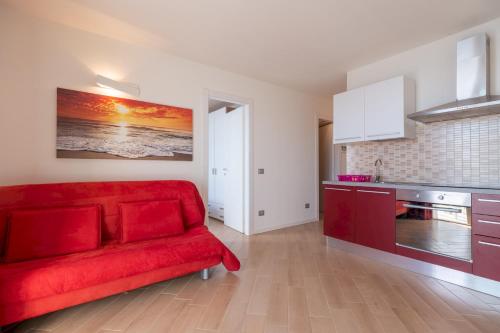 a living room with a red couch and a kitchen at Caravaggio in Parzanica