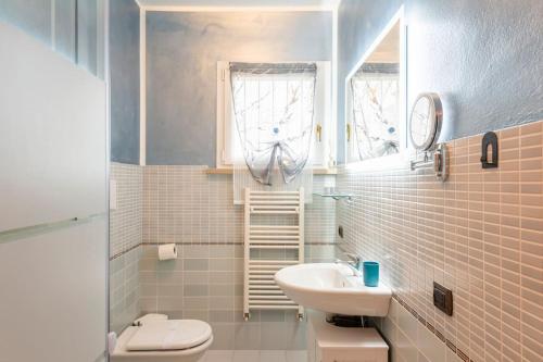 a white bathroom with a sink and a toilet at Limone Apartment - Featuring a Private Garden and Access to a Pool in Barcuzzi