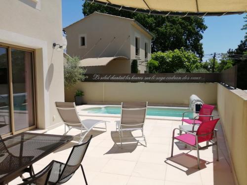 un patio avec des chaises et une table à côté d'une piscine dans l'établissement Le Cabanon de Laura, à LʼIsle-sur-la-Sorgue