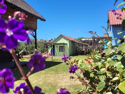 a garden with purple flowers in front of a house at Cabañas Giramundos in Punta Del Diablo