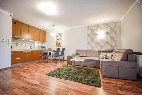 a living room with a couch and a kitchen at Apartamenty na Wyspie - Villa Mistral - Apartamenty z sypialnią i parkingiem in Świnoujście
