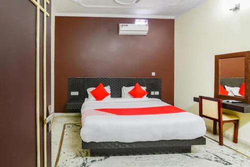 Schlafzimmer mit einem Bett mit roten Kissen und einem Schreibtisch in der Unterkunft Corbett Wildlife Homestay in Rāmnagar